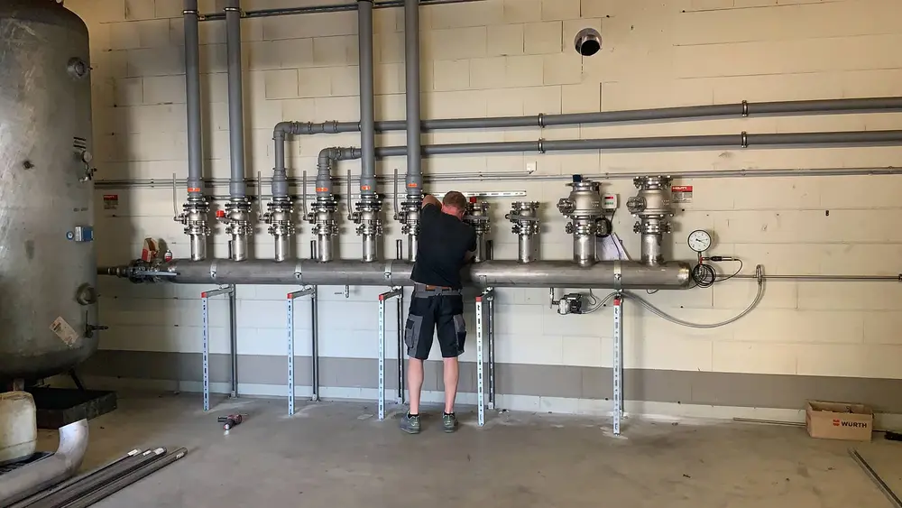 Techniker arbeitet an komplexer Rohrleitungsinstallation