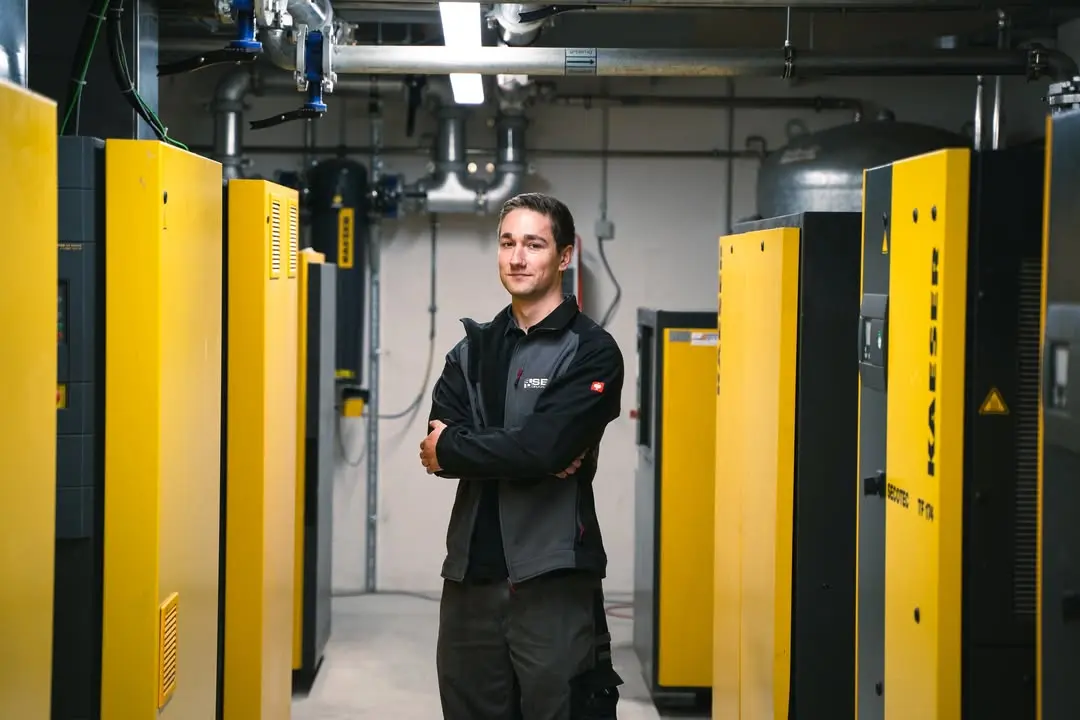 Familienunternehmen Drucklufttechnik Techniker mit verschränkten Armen in Kompressorraum
