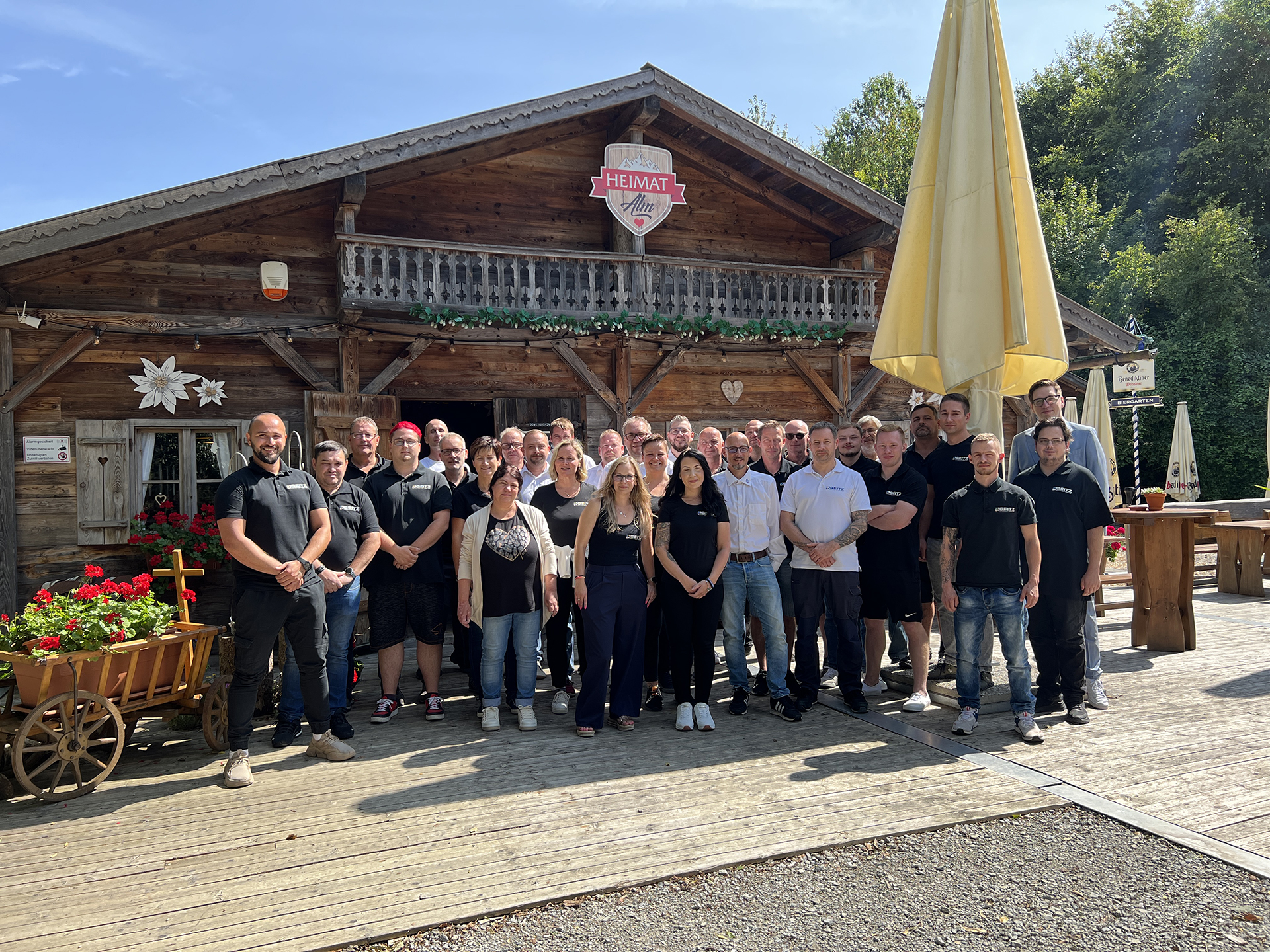 Gruppenfoto des Teams vor einer Berghütte bei Sonne